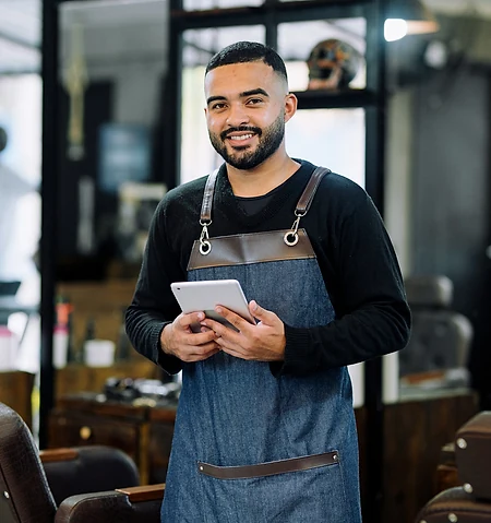 A barber checking new bookings on a tablet between clients.